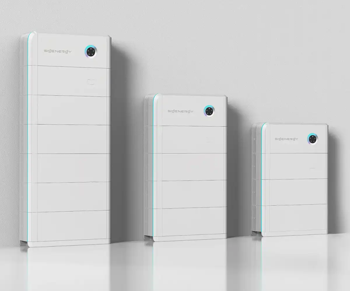Three sleek, white rectangular battery storage units of different sizes are lined up against a light grey wall.